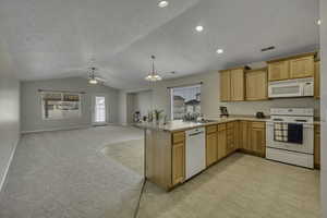 Kitchen with white appliances, open floor plan, light countertops, a peninsula, and healthy amount of natural light
