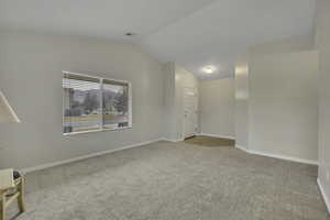 Empty room with light carpet and vaulted ceiling