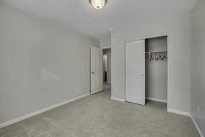 Unfurnished bedroom with light colored carpet and a closet