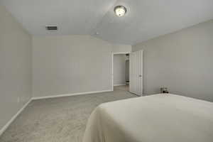 Bedroom featuring light colored carpet and vaulted ceiling