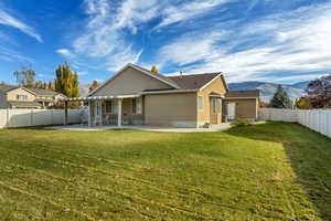 Back of property with a fenced backyard, a mountain view, stucco siding, and a patio