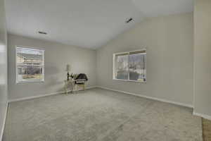 Spare room with light colored carpet, vaulted ceiling, and healthy amount of natural light
