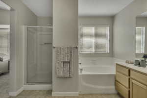 Full bathroom featuring vanity, a stall shower, a garden tub, and light tile patterned flooring