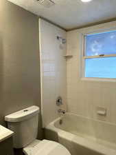 Full bath with a textured wall, vanity, a textured ceiling, and shower / bath combination