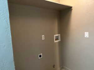 Laundry room with a textured wall, hookup for a washing machine, and hookup for an electric dryer