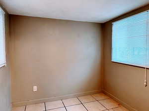 Empty room featuring light tile patterned floors and baseboards
