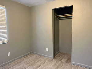 Unfurnished bedroom featuring wood finish floors, a closet, and a textured ceiling
