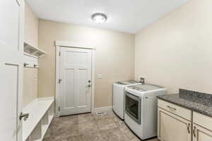 Laundry area with washer and clothes dryer, cabinet space, and light tile patterned floors