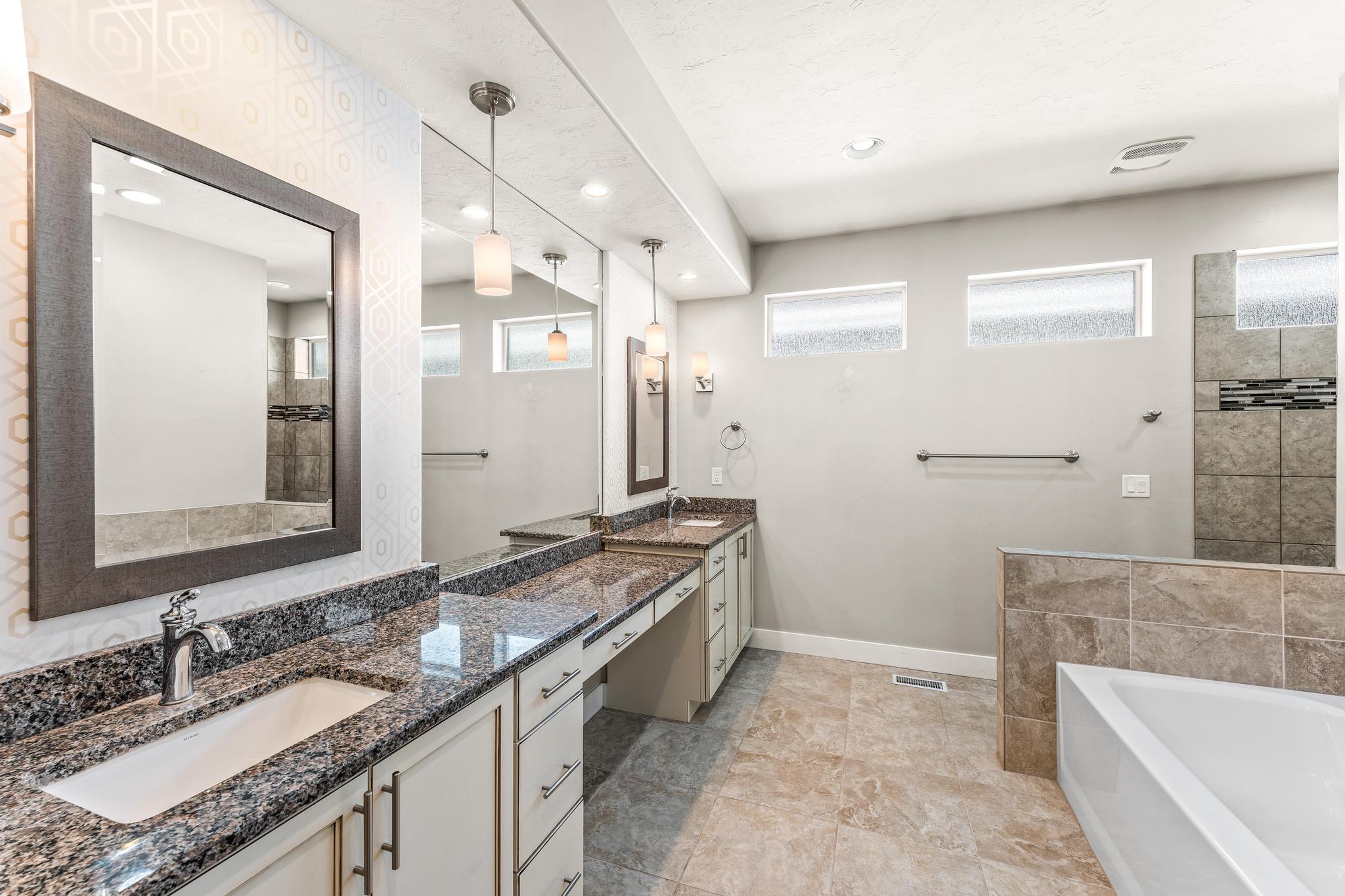 Full bathroom featuring two vanities, double vanity, a bath, and a walk in shower