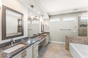 Full bathroom featuring two vanities, double vanity, a bath, and a walk in shower