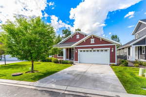 Craftsman inspired home featuring a garage, concrete driveway, and a front yard