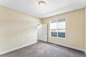 Carpeted spare room featuring baseboards