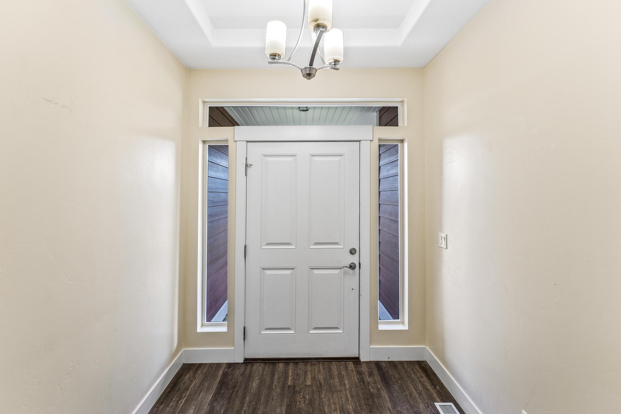 Entryway with dark wood-style floors and a chandelier