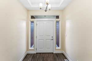 Entryway with dark wood-style floors and a chandelier