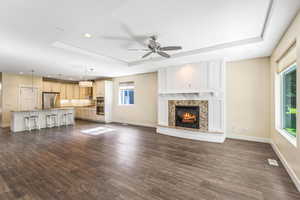 Unfurnished living room with ceiling fan, a raised ceiling, dark wood-style floors, recessed lighting, and a high end fireplace