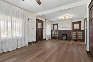 Unfurnished living room with ceiling fan and dark wood-type flooring
