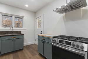 Kitchen featuring stainless steel gas stove, wood counters, dark wood-style floors, and recessed lighting