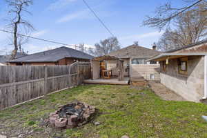 Fenced backyard featuring a wooden deck and an outdoor fire pit