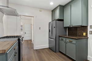 Kitchen featuring stainless steel appliances, decorative backsplash, dark wood-type flooring, wood counters, and recessed lighting