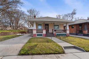 Bungalow-style house with a front lawn, a porch, a chimney, and roof with shingles