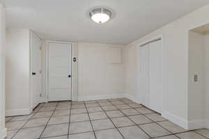 Unfurnished bedroom featuring a closet, a textured ceiling, and light tile patterned floors