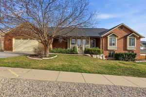 View of front of house featuring brick siding, a porch, concrete driveway, a front lawn, and a garage