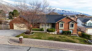View of front of house featuring a mountain view, covered porch, brick siding, a garage, and driveway