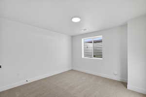 Spare room with light colored carpet and baseboards