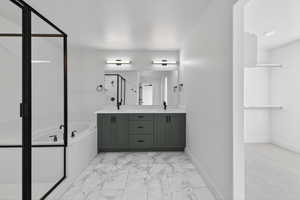 Full bathroom with double vanity, a garden tub, light marble finish floors, a shower stall, and a spacious closet