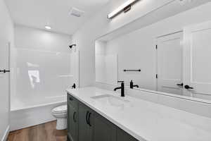 Full bath featuring vanity, dark wood-style flooring, and bathing tub / shower combination