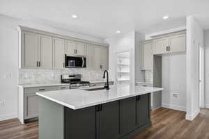 Dual tone kitchen with backsplash, light stone counters, stainless steel appliances, dark wood-style floors, and recessed lighting