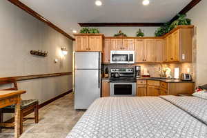 Kitchen with stainless steel appliances, crown molding, decorative backsplash, recessed lighting, and dark stone counters