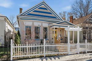 View of front of property featuring a porch, a chimney, a fenced front yard, and brick siding