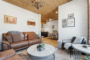 Living room featuring wood finished floors, hanging lights, a ceiling fan, wood walls, and wood ceiling