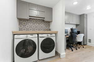 Laundry room featuring an office area, washer and dryer, light wood finished floors, and cabinet space
