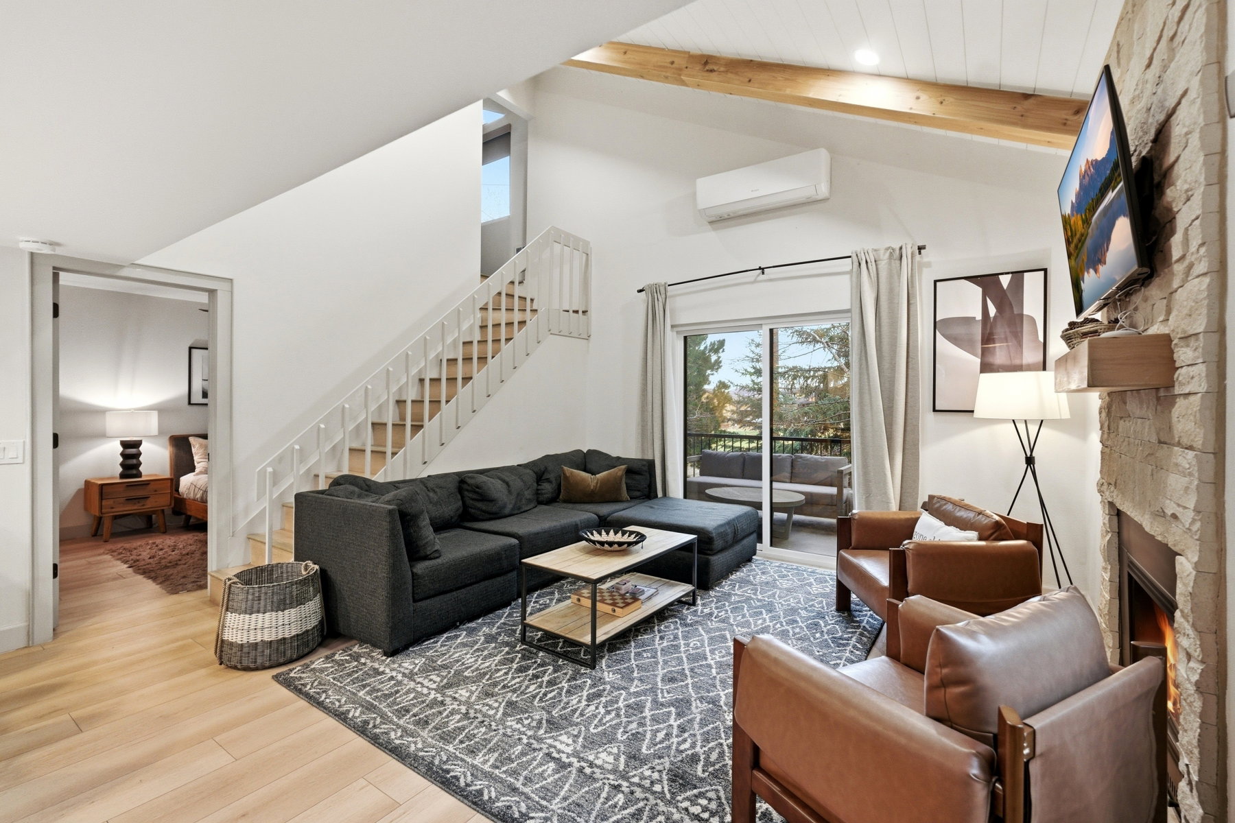 Living area with wood finished floors, a stone fireplace, lofted ceiling, and recessed lighting