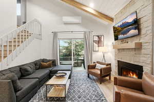 Living area featuring plenty of natural light, a fireplace, and a high wood beamed ceiling