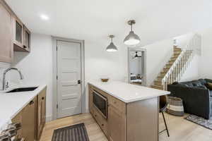 Kitchen featuring a peninsula, a kitchen breakfast bar, stainless steel microwave, light wood-style floors, and open floor plan
