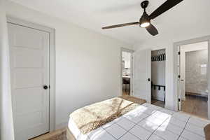 Bedroom featuring a ceiling fan, light tile patterned flooring, and ensuite bathroom