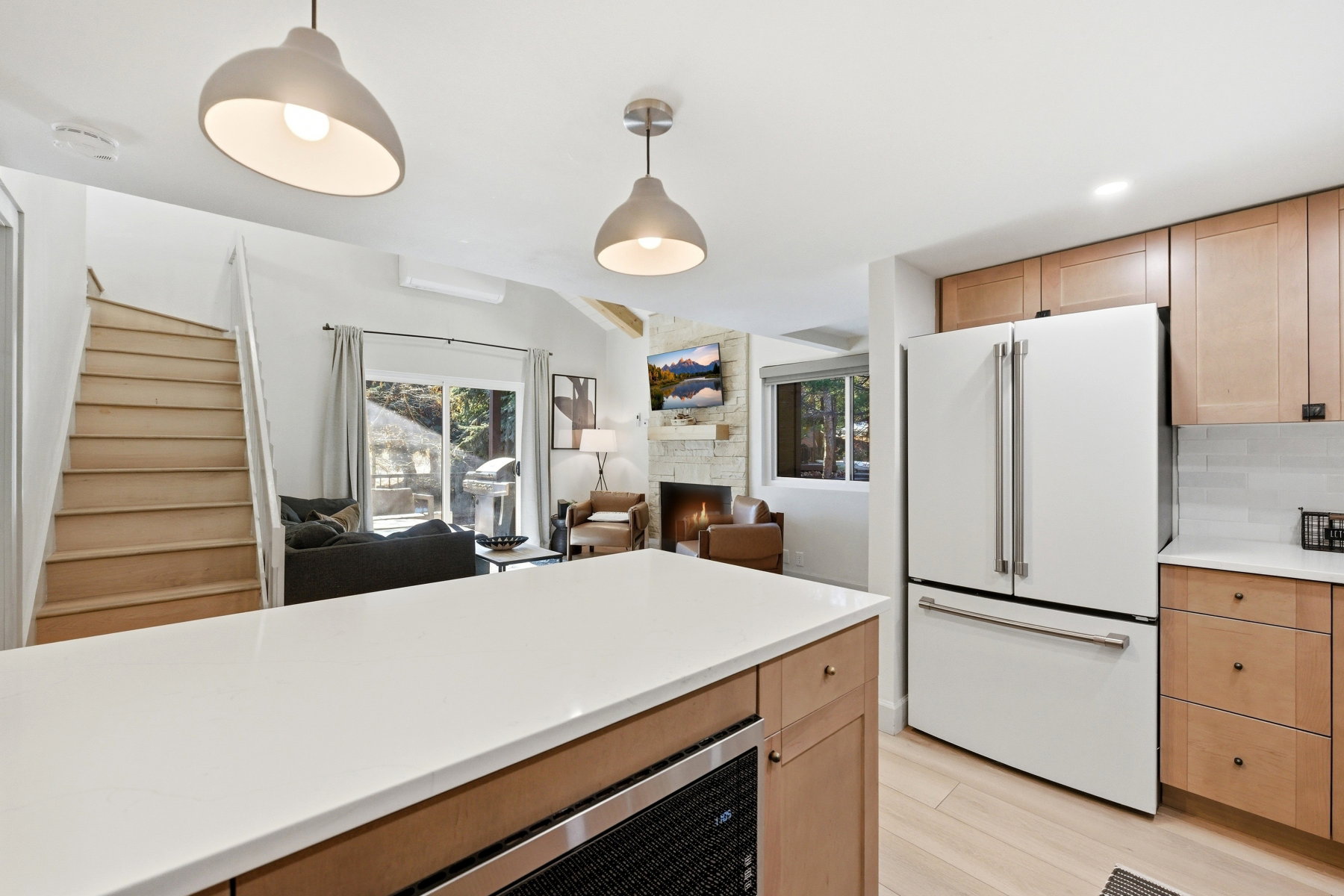 Kitchen featuring high end fridge, light wood-style floors, decorative light fixtures, a fireplace, and open floor plan