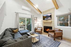 Living area featuring a fireplace, wood finished floors, lofted ceiling, and healthy amount of natural light