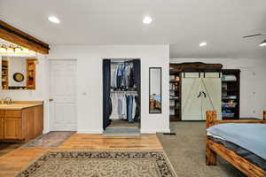 Bedroom featuring a barn door, light wood-type flooring, recessed lighting, and a closet