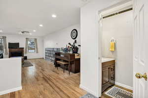 Office space with light wood-style flooring, a fireplace, recessed lighting, and a ceiling fan