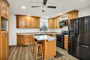 Kitchen featuring stainless steel appliances, light countertops, light wood-style floors, a center island, and a kitchen breakfast bar
