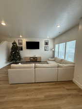 Living area featuring light wood finished floors, a textured ceiling, and recessed lighting