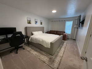 Bedroom featuring light carpet and an office area