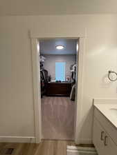 Bathroom with vanity, light wood-type flooring, a spacious closet, and a textured ceiling