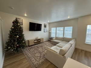 Living room with light wood-type flooring, a textured ceiling, and recessed lighting