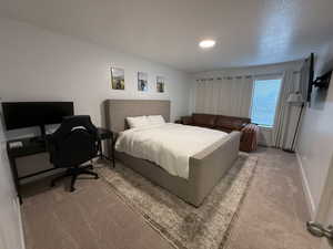 Bedroom with light colored carpet and a desk
