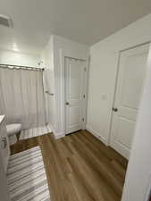 Full bathroom with a shower with curtain, light wood-type flooring, a textured ceiling, and vanity